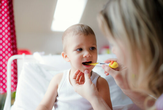 Mother taking temperature of toddler son at home