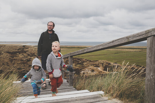 Father and his children walking up stairs among the dunes, Sylt, Germany