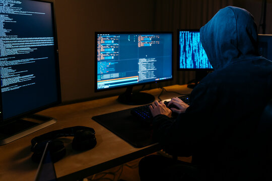 Hacker wearing hoodie working on computer while sitting at office
