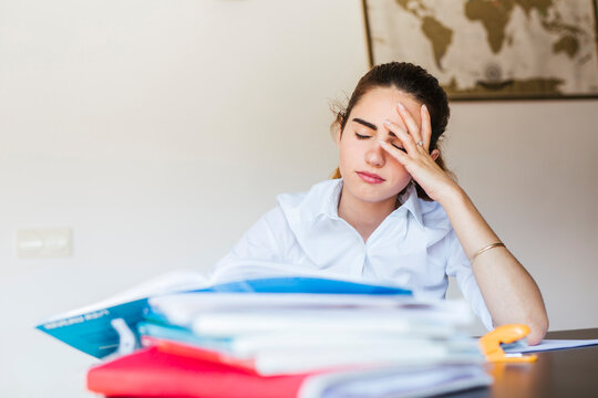 Frustrated female student with documents at desk at home