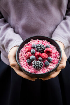 Girl holding bowl with overnight oats mit frozen berries