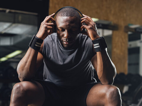 Athlete sitting in gym, wearing headphones, concentrating
