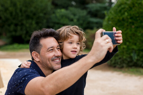 Happy father and son on taking a selfie in park