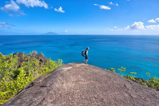 Anse major nature trail, sunny hot day, single woman taking photos of panoramic view, Mahe island, Seychelles