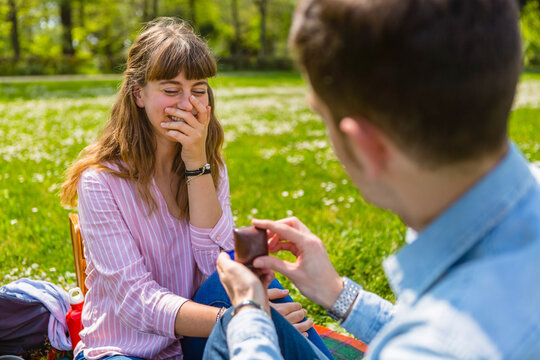 Young man proposing to his girlfriend in a park