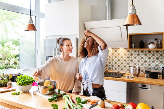 Businesswoman with colleague tasting spaghetti in office kitchen