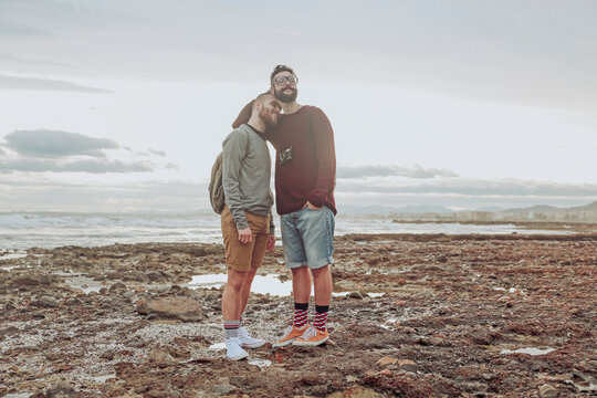 Happy young gay couple standing on the beach