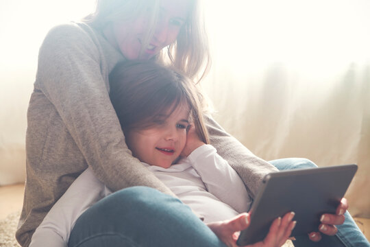 Mother and little daughter using tablet at home