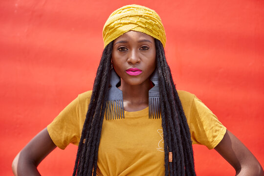 Portrait of woman in a long dreadlocks in front of a red wall