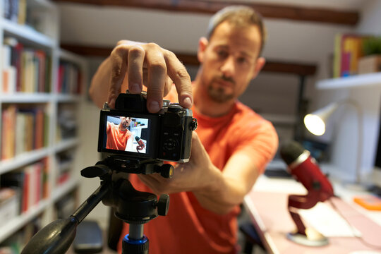 Mid adult man adjusting camera for recording video tutorial