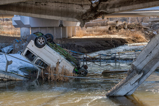 Irpin, Ukraine - 07 March 2026: View of the Irpin Bridge, shattered and collapsed, with a vehicle submerged in the river's murky waters, a stark testament to conflict.