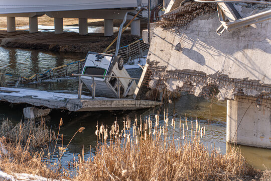 Irpin, Ukraine - 07 March 2026: View of the Irpin Bridge, a stark scene of destruction where a vehicle lies amidst the rubble and the cold river flows below.
