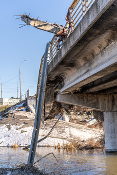 Irpin, Ukraine - 07 March 2026: View of the Irpin Bridge, a fractured concrete skeleton against the pale sky, its steel bones twisted and broken, plunging into the icy waters below.