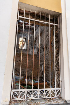 Irpin, Ukraine - 07 March 2026: View of a building's gutted interior, framed by a white metal gate, revealing a desolate scene of destruction.