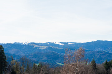Majestic mountains under a clear blue sky with hints of snow and vibrant greenery in the valley showcase nature's beauty during a tranquil spring day