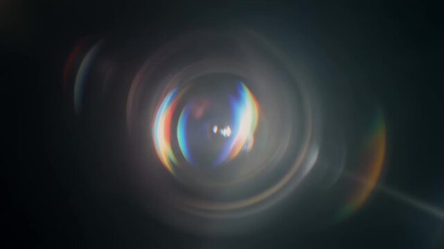 Rotating prismatic lens flare circles in darkness.