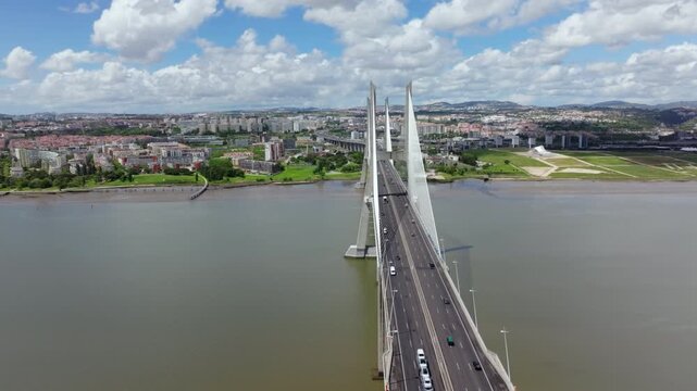 Sweeping aerial drone shot of the Vasco da Gama bridge in Lisbon. The camera flies alongside the iconic structure, revealing its scale over the Tagus River with the city in the background