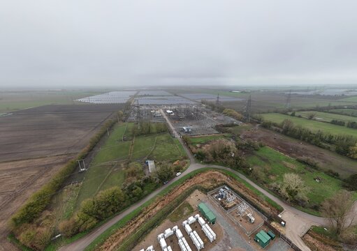 Aerial view of a substation nestled between solar farms and fields, the juxtaposition of power and nature, Burwell, United Kingdom.