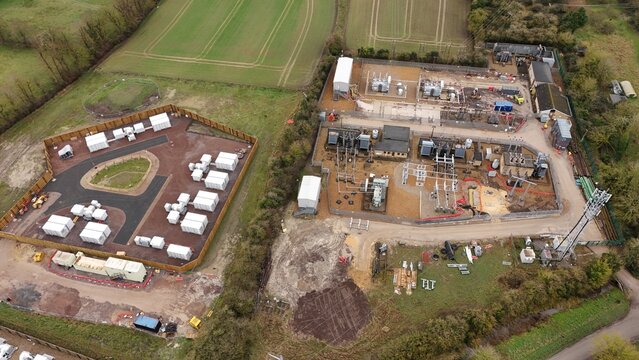 Aerial view of the juxtaposition of energy infrastructure and agrarian landscape, a modern substation and Battery Energy Storage System BESS nestle beside a solar farm, Burwell, United Kingdom.