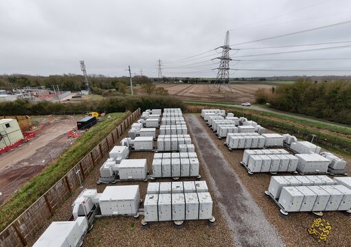 Aerial view of battery energy storage systems casting long shadows under a vast sky near electrical sub station, Burwell, United Kingdom.