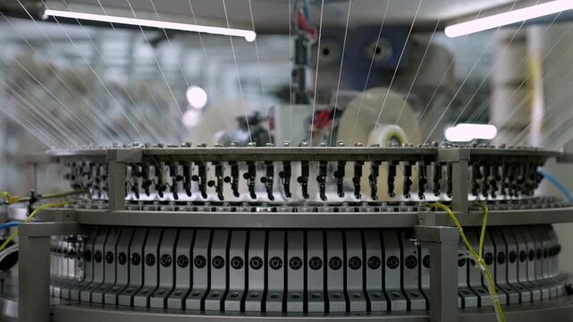 Automated circular knitting machine operating inside a modern textile factory. Professional industrial footage reflecting advanced textile technology and large scale manufacturing.