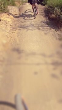 Kids having fun driving downhill MTB mountainbike on sunny day - vertical video