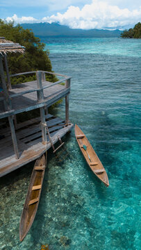 Aerial view of crystal-clear turquoise waters meet wooden stilts and traditional canoes, a tranquil island paradise beckons from the depths, Gizo, Western Province, Solomon Islands.
