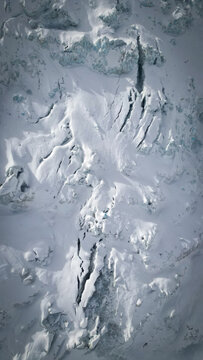 Aerial view of stark, snow-covered crevasses cutting through the icy expanse of Vallee Blanche Glacier, revealing deep blue depths, Chamonix-Mont-Blanc, Auvergne-Rhone-Alpes, France.
