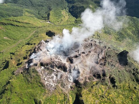 Aerial view of La Grande Soufriere volcano, with its stark, scarred landscape contrasting against the verdant green hillsides, Guadeloupe, Guadeloupe.