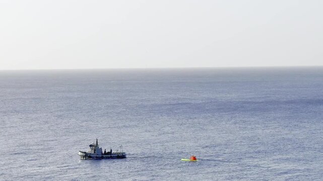 Small boat with an exploratory scientific submarine towing swimmer in open ocean
