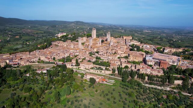Aerial view of the medieval towers and buildings of San Gimignano, a Tuscan hill town, set against a backdrop of rolling green hills, San Gimignano, Tuscany, Italy.