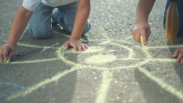 Children drawing with chalk on street. Siblings sketch colorful art outdoors. Kids enjoy creative activity street with chalk. Fun childhood moment as children draw together. Street art chalk by kids.