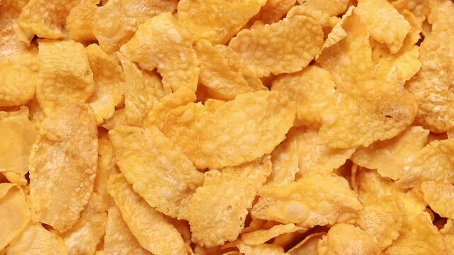 Slowly rotating pile of golden cornflakes cereal. Top view shot