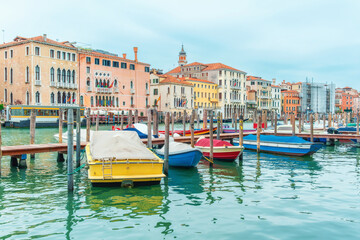 Fototapeta premium Small boats moored along wooden poles on Grand Canal in Venice old town, Italy with historic waterfront palaces and buildings. Traditional canal transport, Venetian architecture and historic city