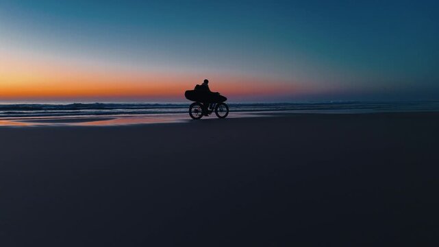 Bassin d'Arcachon, Gironde, Nouvelle-Aquitaine, France, un homme fait du v&eacute;lo seul sur une plage d&eacute;serte en Aquitaine, vue drone de profil, coucher de soleil