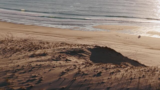 Bassin d'Arcachon, Gironde, Nouvelle-Aquitaine, France, un homme fait du v&eacute;lo seul sur une plage d&eacute;serte en Aquitaine, vue drone de profil