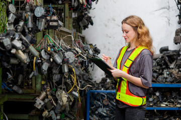 Worker holding a clipboard and checking electronic scrap in the factory