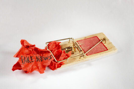 Dangers of Fake News attack,with triggered mousetrap and fake news sign.Education,learning,fight stupidity through education