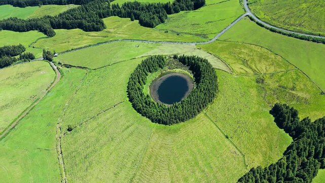 Drone shot over round lake Pau Pique lagoon surrounded by forest, Azores