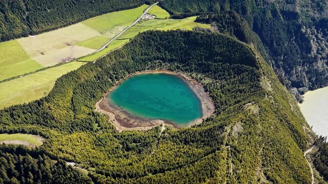 Small crater lake surrounded by forest inside volcanic slopes of Sete Cidades on Sao Miguel Island, aerial view