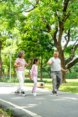 Obraz premium Vertical image of Asian senior man and woman also the girl action of stretching the waist and they look happy in public park together