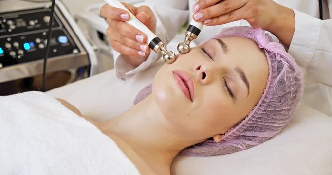 Beautiful woman receiving facial microcurrent treatment at spa salon. Beautician using electrical impulses for facial procedures. Woman in spa salon. Woman in a spa salon on cosmetic procedures.