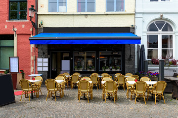 Old cozy street with tables of restaurant in Bruges (Brugge), West Flanders province, Belgium. Cityscape of Bruges.