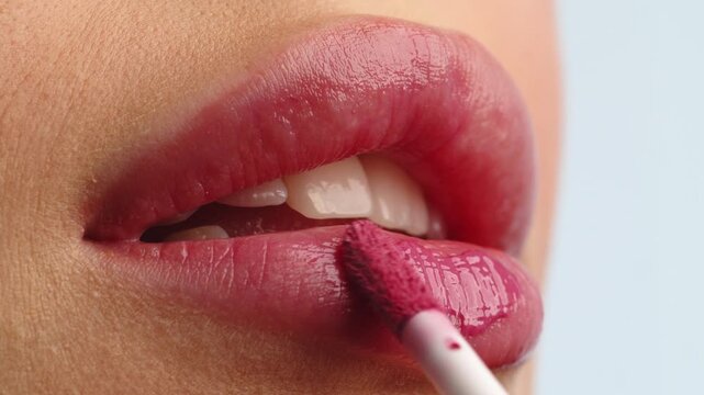 Closeup shot stylist applies lipstick  to the lips of the female model. Woman making make up applying lipstick on a lip. Professional makeup. Tutorial makeup master class. Making mua. Slow motion.