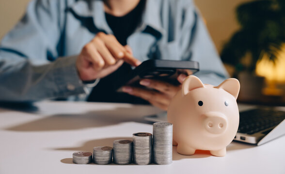 Piggy bank coins calculator laptop person saving money finance investment growth business table indoor technology casual office currency stack counting planning budget financial planning economy