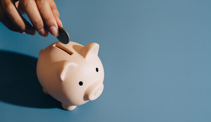 Piggy bank coin hand saving finance money blue background close up personal finance investment banking cash budget economy wealth financial planning currency deposit financial security thrift pig © JK_kyoto