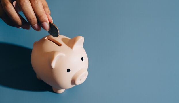 Piggy bank coin hand saving finance money blue background close up personal finance investment banking cash budget economy wealth financial planning currency deposit financial security thrift pig