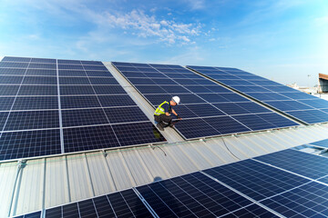 Rooftop solar panel installation worker inspecting photovoltaic panels under a clear blue sky © FotoArtist