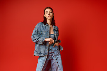 Fototapeta premium Stylish young woman in denim outfit poses confidently in a vibrant studio setting