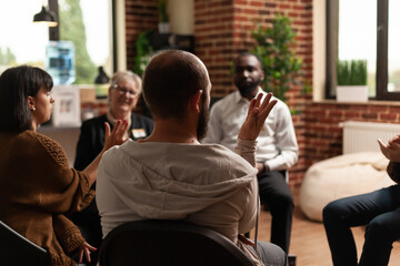Person sharing achievement with group of people at aa meeting, sitting in circle. Man at therapy...